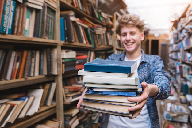 Retrato de un joven estudiante que ofrece un libro.