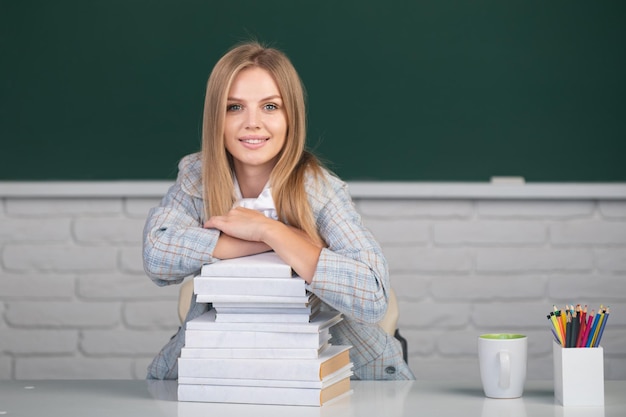 Retrato de una joven estudiante segura y atractiva que estudia en el aula de la escuela Linda estudiante con libros sobre fondo de pizarra con espacio para copiar