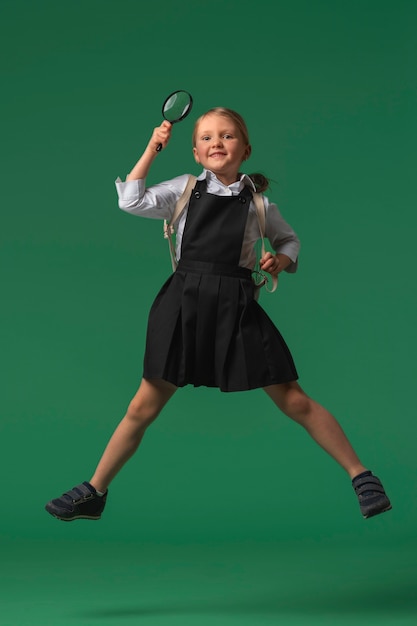 Foto retrato de una joven estudiante con uniforme escolar saltando en el aire