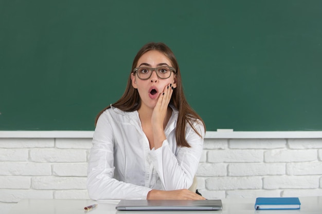 Retrato de una joven estudiante universitaria sorprendida en el aula en clase con fondo de pizarra