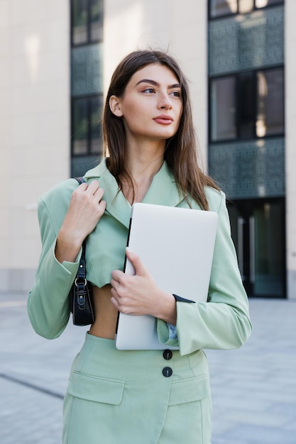 Retrato de una joven exitosa con una computadora portátil posando afuera