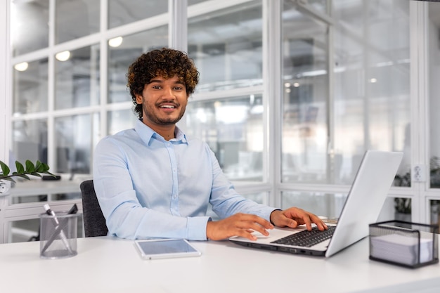 Retrato de un joven y exitoso hombre de negocios contemporáneo dentro de un hombre de oficina en el lugar de trabajo sonriendo y