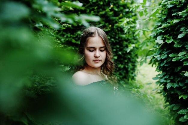 Retrato de una joven fabulosa con un bonito vestido con un elegante peinado rizado posando en el bosque o en el parque