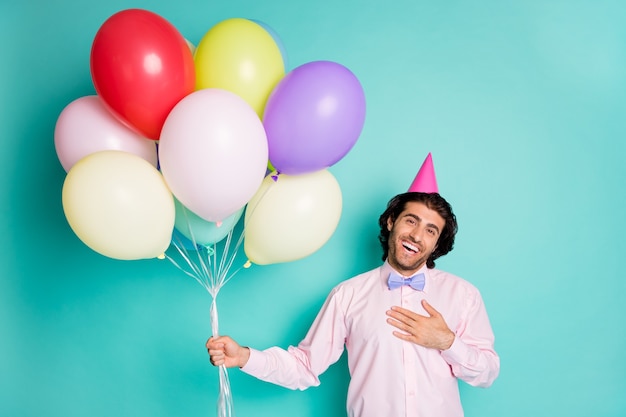 Retrato de joven felicitar al hombre de la mano en el cono de ropa formal de corazón traer globos de colores aislados sobre fondo de color turquesa