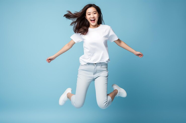 Retrato de una joven feliz y alegre vestida con una camiseta blanca celebrando el éxito y la victoria