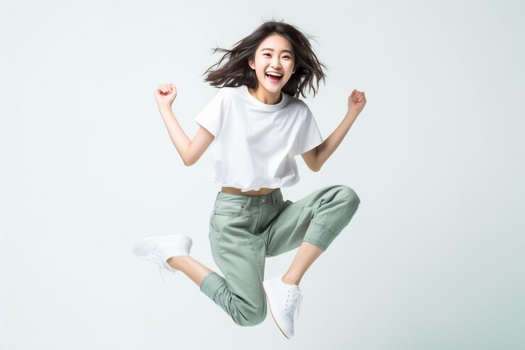 Retrato de una joven feliz y alegre vestida con una camiseta blanca celebrando el éxito y la victoria