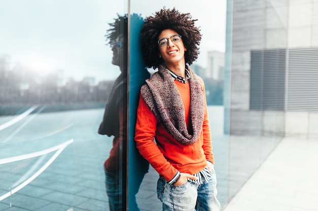 Foto retrato de un joven feliz apoyado en un edificio moderno