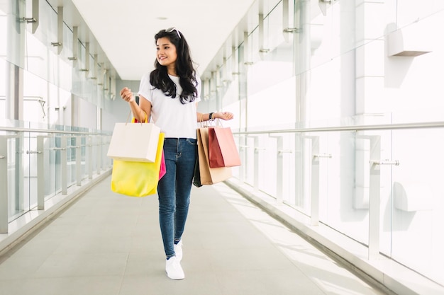 Retrato de una joven feliz con bolsas de compras en el centro comercial