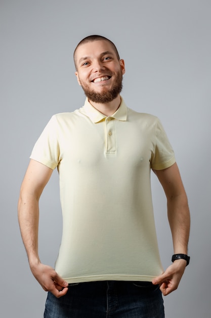 Foto retrato de un joven feliz en camiseta amarilla mocap en gris.