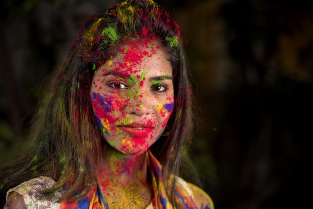 Retrato de una joven feliz con una cara colorida con motivo del festival de color Holi.