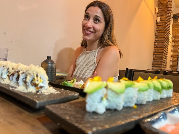 retrato de una joven feliz cenando sushi en un restaurante japonés con cara feliz