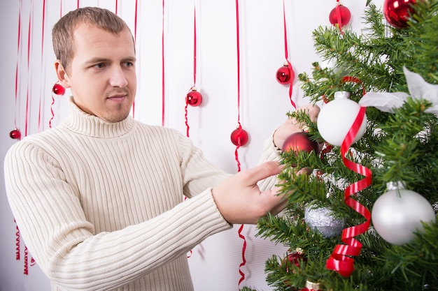 Retrato de joven feliz decorar el árbol de Navidad