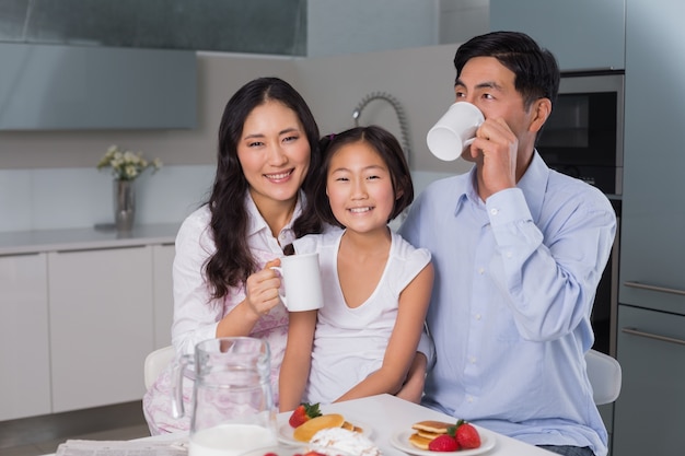 Retrato de una joven feliz disfrutando de desayuno con los padres