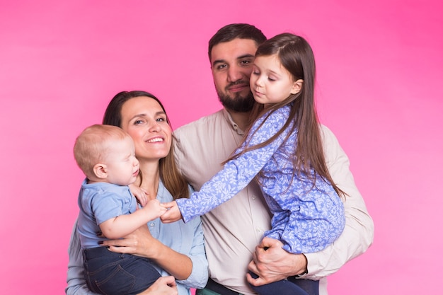 Foto retrato de joven feliz familia de raza mixta sobre pared rosa