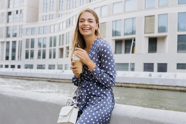 Retrato de una joven feliz La modelo bebe café helado en verano en la calle