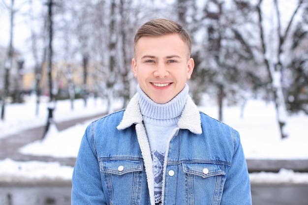 Retrato de joven feliz en el parque cubierto de nieve en vacaciones de invierno