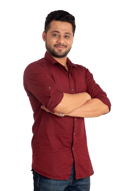 Retrato de un joven feliz posando con los brazos cruzados o las manos cruzadas sobre un fondo blanco.