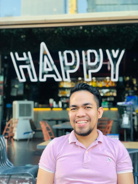 Foto retrato de un joven feliz sentado frente al restaurante