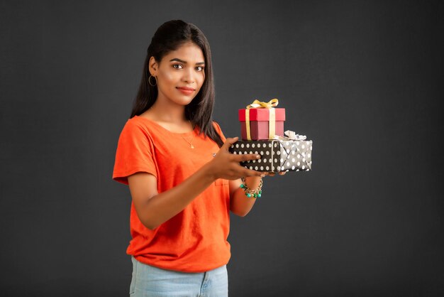 retrato, de, joven, feliz, sonriente, niña, tenencia, caja obsequio, en, un, fondo gris