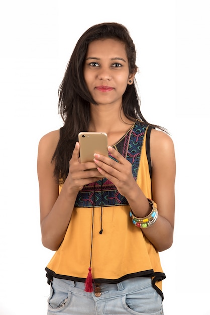 Retrato de una joven feliz con teléfono móvil aislado sobre fondo blanco.