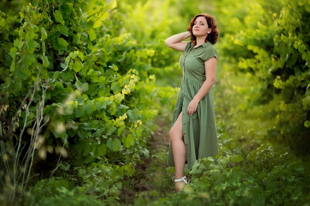 Retrato de una joven feliz en vestido verde en las montañas en los viñedos