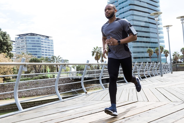 Retrato de joven en forma y deportivo corriendo en la ciudad.