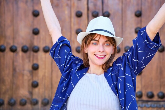 Retrato de una joven de frente sonriendo con un sombrero blanco y una blusa azul mirando a la cámara