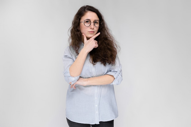 Retrato de una joven con gafas. Hermosa joven sobre un fondo gris.