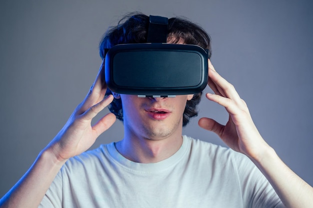 Retrato de un joven de las gafas de realidad virtual sobre un fondo de pared gris. El concepto de juegos con la máscara de la realidad virtual.