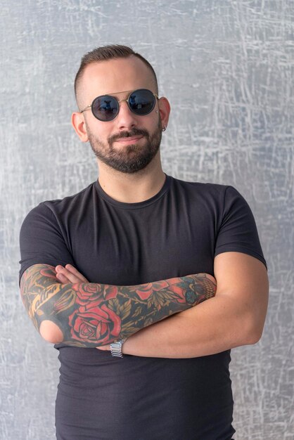 Foto retrato de un joven con gafas de sol mientras está de pie contra la pared