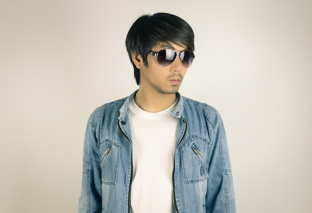 Retrato de un joven con gafas de sol de pie contra la pared