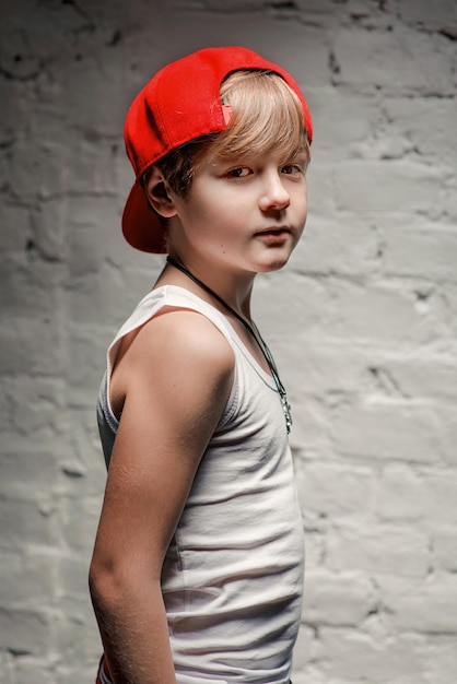 Retrato de un joven y genial hip hop con sombrero rojo y pantalones rojos y camisa blanca en el desván