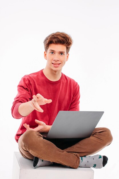 Foto retrato de un joven gestando mientras está sentado contra un fondo blanco