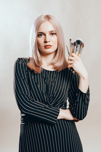 Retrato de una joven guapa con pinceles de maquillaje