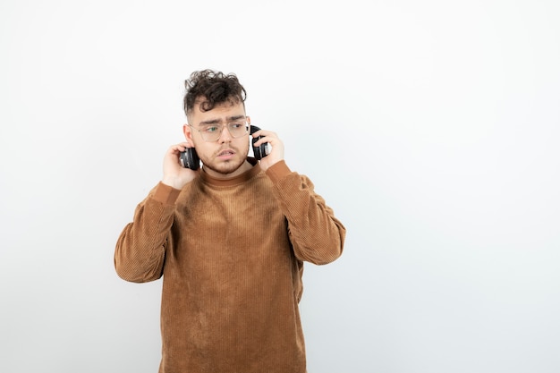 Retrato de joven guapo en auriculares de pie sobre blanco.