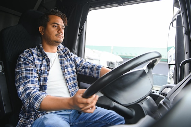 Foto retrato de un joven y guapo camionero indio el concepto de logística y transporte de mercancías