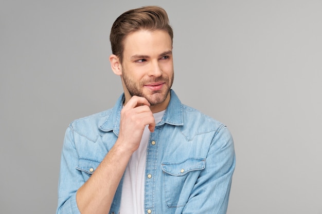 Retrato de joven guapo en camisa de jeans sobre pared ligera