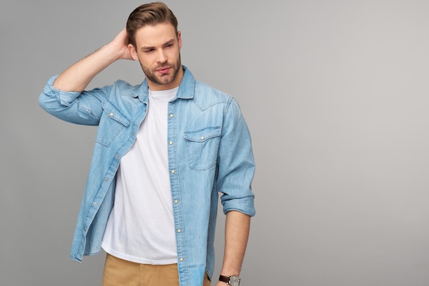 Retrato de joven guapo en camisa de jeans sobre pared ligera