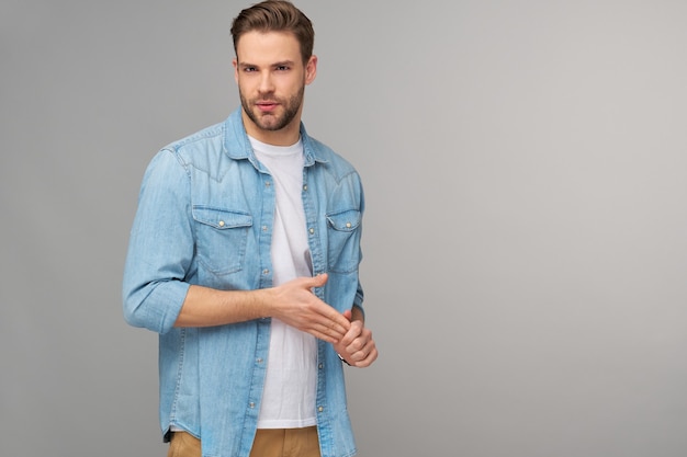 Retrato de joven guapo en camisa de jeans sobre pared ligera