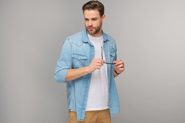 Retrato de joven guapo en camisa de jeans sobre pared ligera