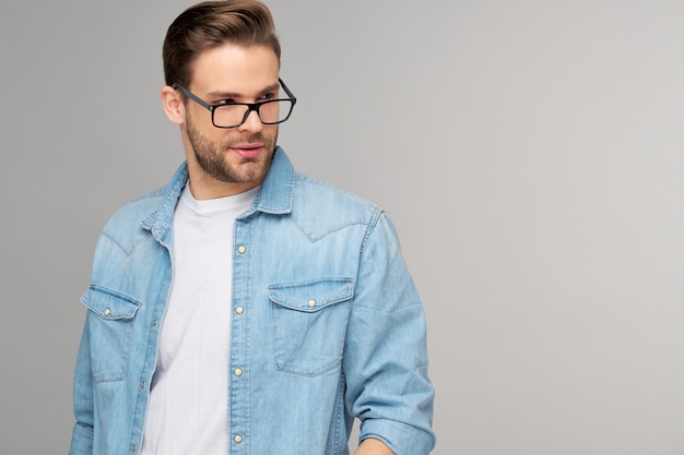 Retrato de joven guapo en camisa de jeans sobre pared ligera