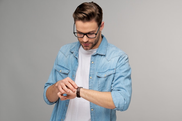 Retrato de joven guapo en camisa de jeans sobre pared ligera