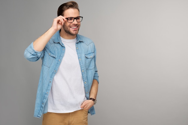 Retrato de joven guapo en camisa de jeans sobre pared ligera