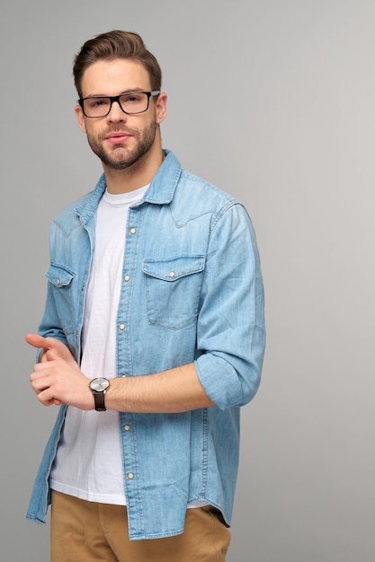 Retrato de joven guapo en camisa de jeans sobre pared ligera