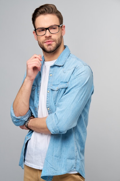 Retrato de joven guapo en camisa de jeans sobre pared ligera