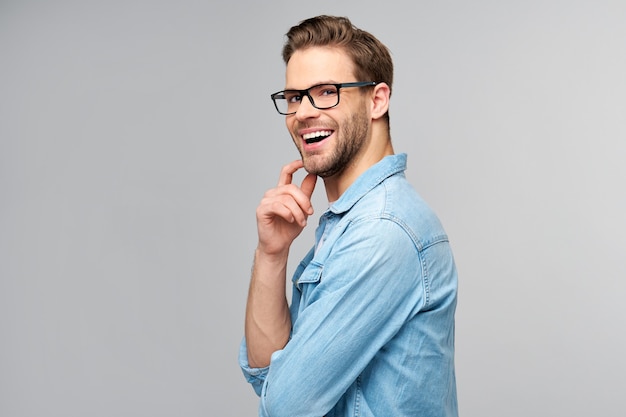 Retrato de joven guapo en camisa de jeans sobre pared ligera