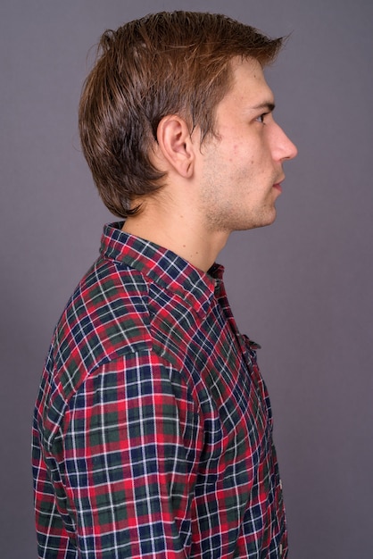 Foto retrato de joven guapo contra la pared gris