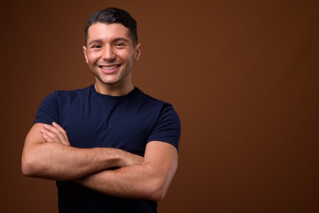 Foto retrato de joven guapo contra la pared marrón