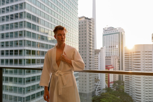 Retrato de joven guapo disfrutando de la vista de la ciudad desde el balcón