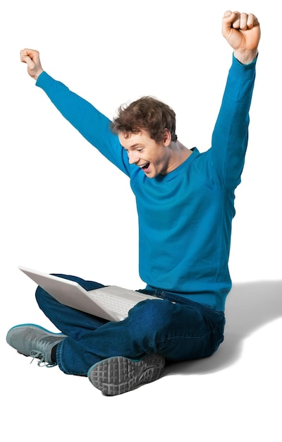 Retrato de joven guapo feliz sentado con el portátil con los brazos extendidos aislado en blanco